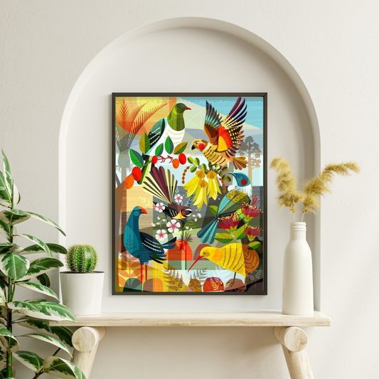 Bright colourful art print by Ellen Gigenbach featuring native New Zealand birds and plants. Frame in a narrown black frame and hanging on a white arched alcove above a wooden table with planst on either side.