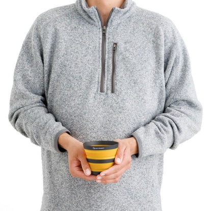 Person holding a Sea to Summit collapsible mug in yellow.