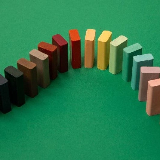 Multi coloured display of rectangle block crayons set out like dominoes in a rainbow.