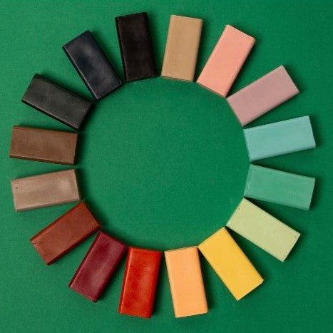 16 coloured rectangle block crayons layed out in shade coloured in a circle.