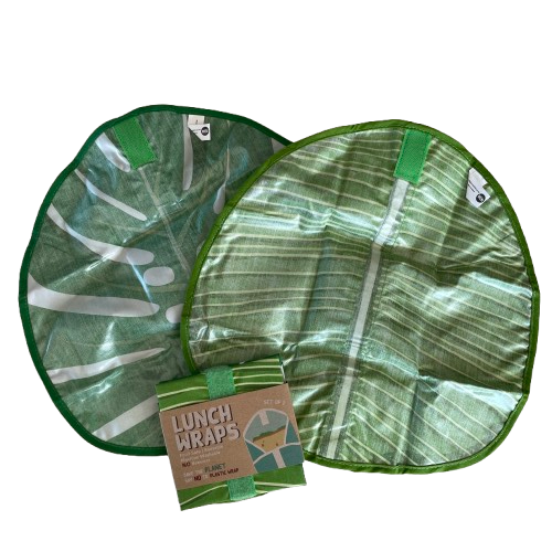 Pair of green leaf print eco friendly lunch wraps unfolded with the inside showing and a set folded up next to them.