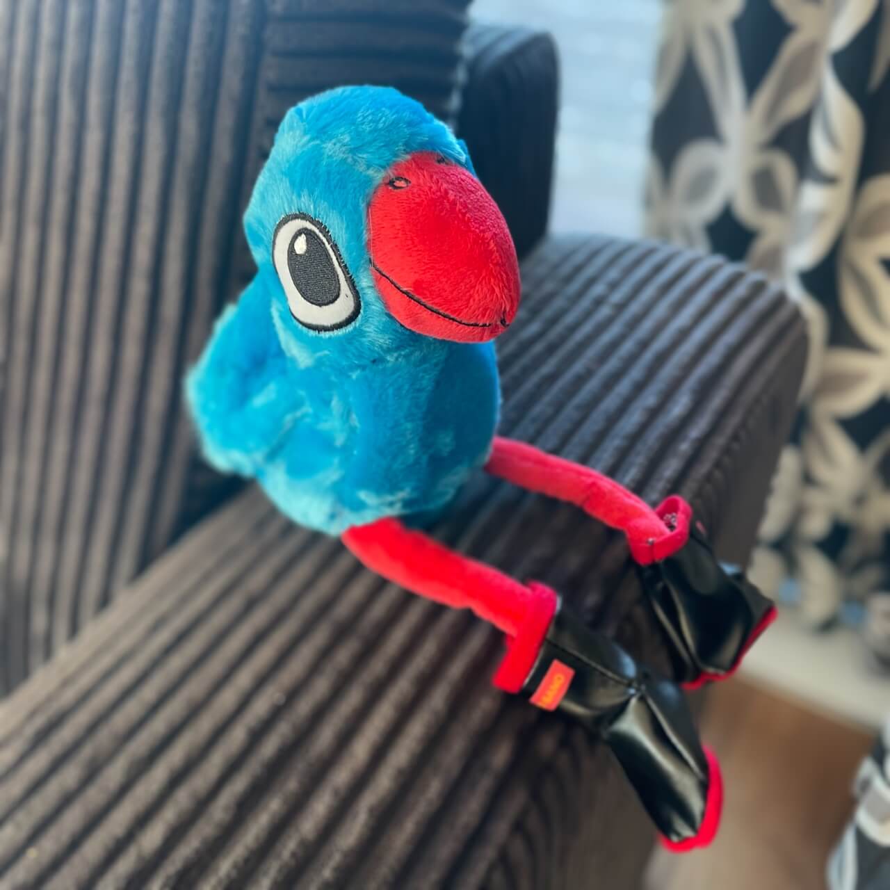 Plush pukeko toy wearing Redband gumboots sitting on the arm of a couch.