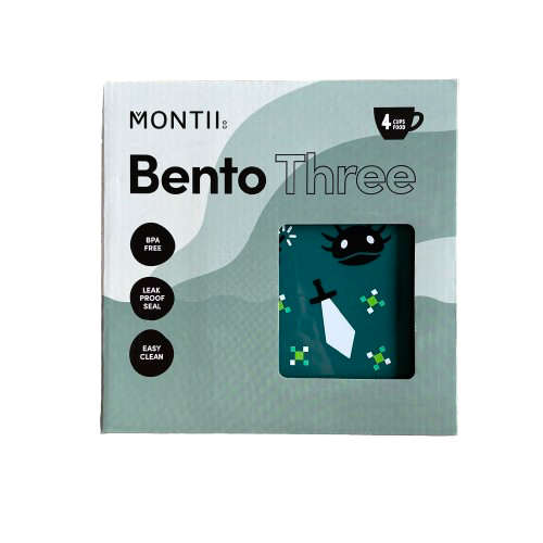 Front of packaging from a MontiiCo Bento Three lunchbox showing the dark green lunchbox inside with a gamer print on the lid.