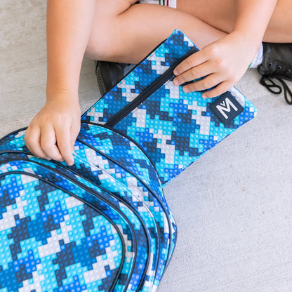 Close up of a childs hands putting a blue block print pencil case into a matching backpack.