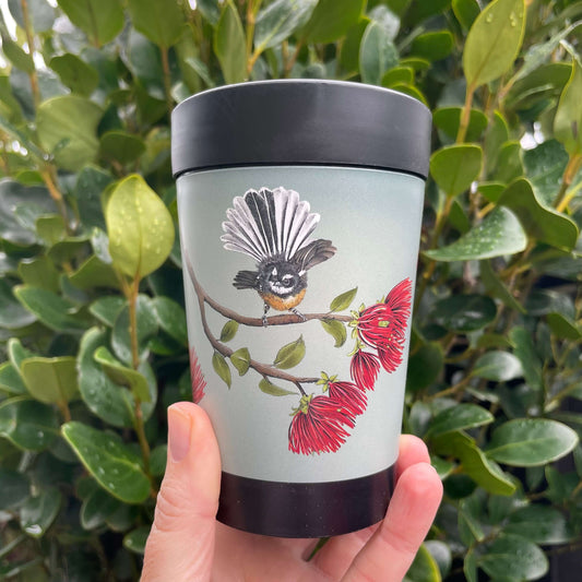 Black reusable coffee cup with a blue grey wrap around the centre with a fantail resting on a pohutukawa branch.