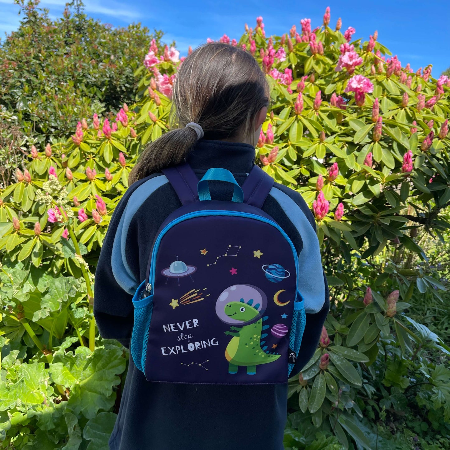 Blue kids backpack with an astronaut dinosaur print and the words "never stop exploring" on it.