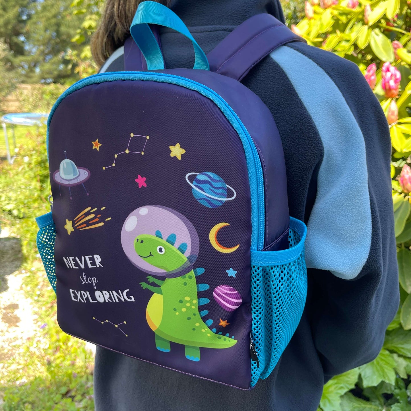 Blue kids backpack with an astronaut dinosaur print and the words "never stop exploring" on it.