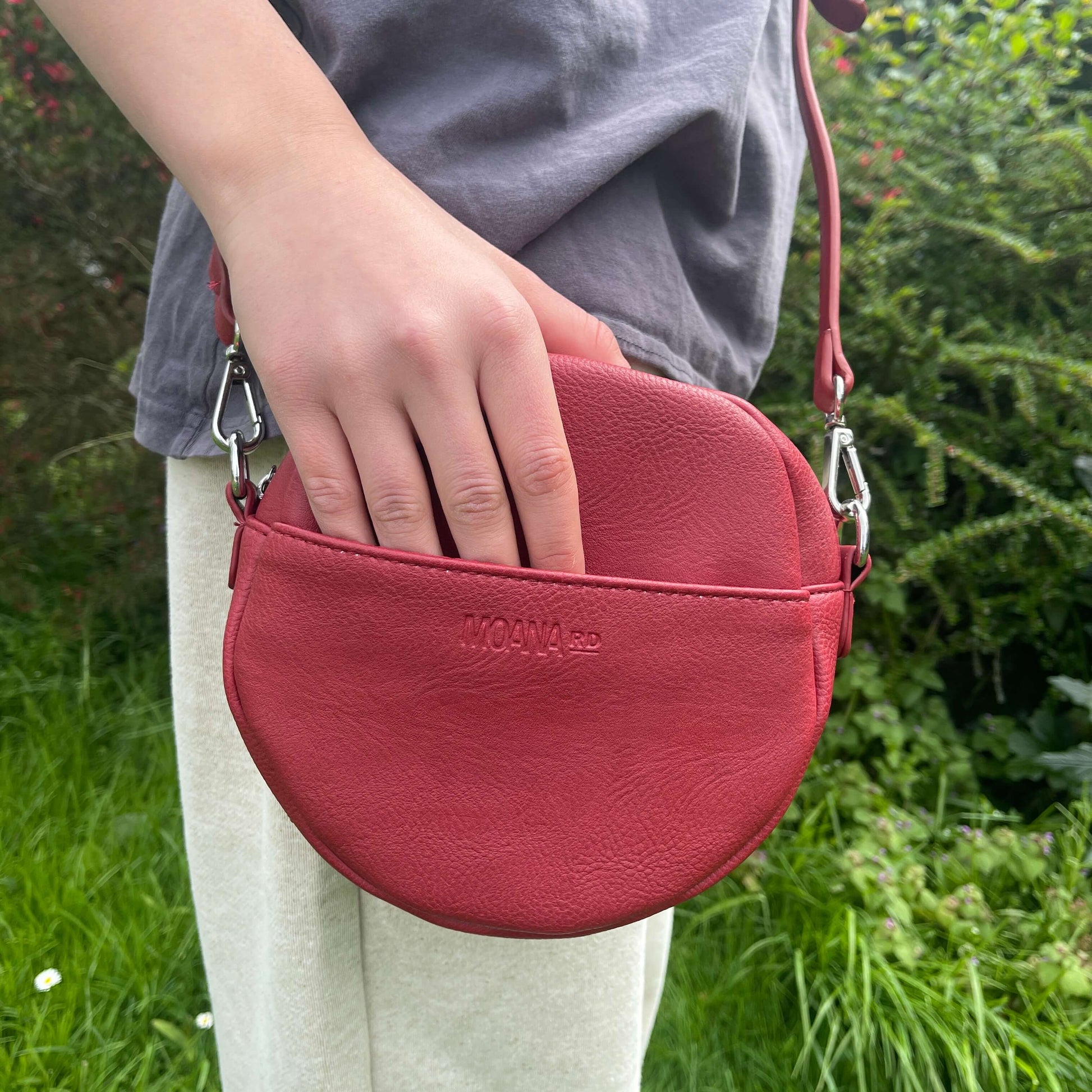 Red circular handbag with front pocket.