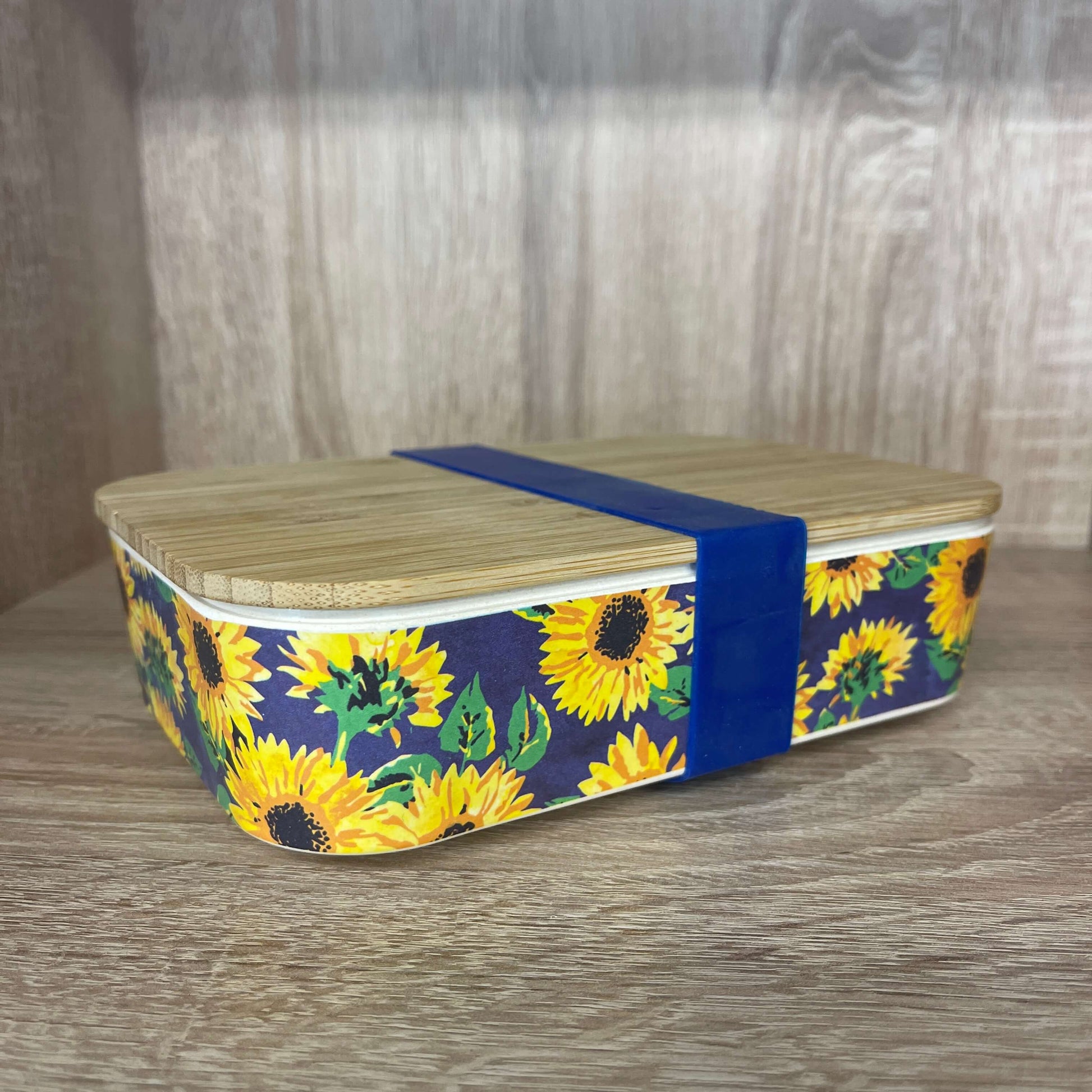 Bamboo lunchbox with sunflower print and blue silicone band.