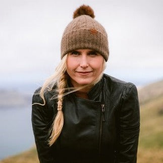 Lady wearing brown knit beanies with pompoms.